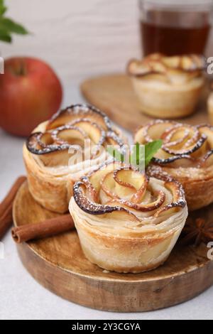 Roses de pomme fraîchement cuites avec menthe, cannelle et étoile d'anis sur la table lumineuse, gros plan Banque D'Images