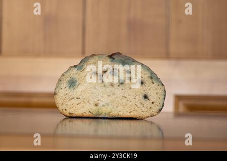 Pain coupé rassis, gâté et moisi sur une table de cuisine. Gros plan, faible profondeur de champ, personne. Banque D'Images