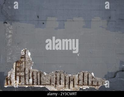 Un vieux mur en béton peint en gris avec des barres de renfort en acier rouillé corrodant causant des dommages à la structure Banque D'Images