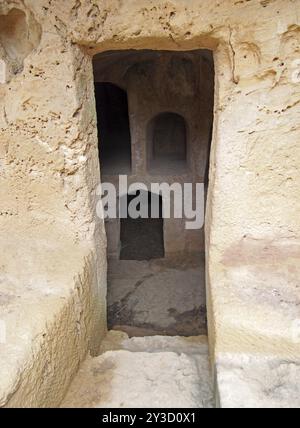 Une porte étroite creusée dans la roche avec des marches menant à des chambres souterraines sombres sur les tombes des rois à paphos chypre Banque D'Images