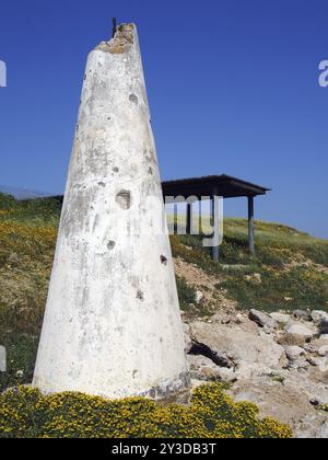 Une structure en béton conique blanc brisé à côté d'un abri sur les falaises côtières entourée de fleurs printanières jaunes et d'un ciel bleu vif à paphos Banque D'Images