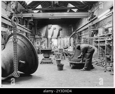 Vue intérieure de Whitechapel Bell Foundry, 32-34 Whitechapel Road, Whitechapel, Tower Hamlets, Greater London Authority, 1974 ; montrant un homme travaillant à une grande cloche. Banque D'Images