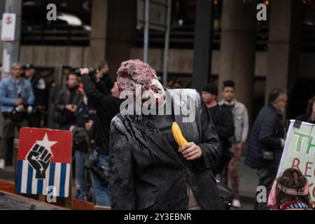 Melbourne, Australie. 13 septembre 2024. Un manifestant déguisé et agissant comme un zombie tient une banane pendant le rallye. Pour le dernier jour de Land Forces, une exposition sur les armes, les manifestants se déguisaient en zombies et se savouraient de faux sang. Ils ont mis des chaussures d'enfants devant les lignes de police pour représenter les enfants palestiniens tués. Pendant la manifestation, les manifestants soufflent également des bulles en criant à la police "vous n'avez pas d'amis, nous avons des bulles". Crédit : SOPA images Limited/Alamy Live News Banque D'Images