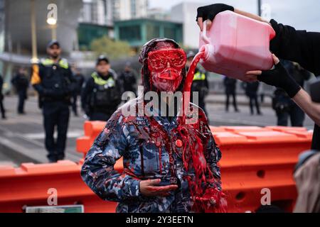 Melbourne, Australie. 13 septembre 2024. Un manifestant portant l'uniforme de l'armée de l'air ADF est arrosé de faux sang pour montrer les effets des profits de guerre pendant le rassemblement. Pour le dernier jour de Land Forces, une exposition sur les armes, les manifestants se déguisaient en zombies et se savouraient de faux sang. Ils ont mis des chaussures d'enfants devant les lignes de police pour représenter les enfants palestiniens tués. Pendant la manifestation, les manifestants soufflent également des bulles en criant à la police "vous n'avez pas d'amis, nous avons des bulles". (Photo de Gemma Hubeek/SOPA images/SIPA USA) crédit : SIPA USA/Alamy Live News Banque D'Images