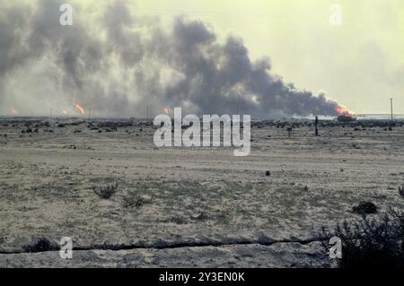 Première Guerre du Golfe : 7 mars 1991 la combustion de puits de pétrole et de fumée forment une toile de fond pour les véhicules abandonnés de l'armée irakienne dans le désert pollué par le pétrole dans le champ pétrolier de Burgan, au sud de Koweït City. Banque D'Images