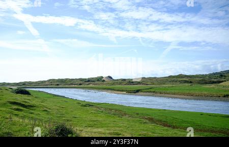 La rivière Ogmore comme elle approche de son estuaire, avec la Big Dipper (dune de sable Merthyr Mawr) au loin. Banque D'Images