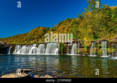 Les chutes de Sandstone Falls cascades au-dessus des rochers avec un feuillage d'automne vibrant et un ciel bleu clair en Virginie occidentale. Banque D'Images