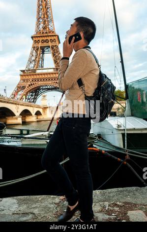 Paris, France, jeune touriste chinois, étudiant, parler sur smartphone, iPhone, Tour Eiffel, à l'arrière, scène Seine, tech products summer Banque D'Images