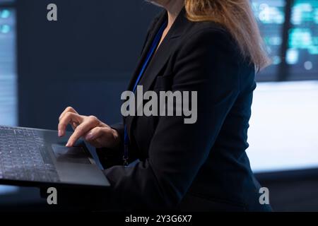 Informaticien dans la salle de serveur à l'aide d'un ordinateur portable pour mettre en œuvre et maintenir des mesures de sécurité, protégeant les systèmes contre l'accès non autorisé. Gros plan sur les employés du datacenter effectuant des mises à niveau matérielles Banque D'Images