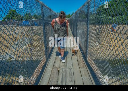 Sacramento, CA. 31 juillet 2024. Après avoir reçu une notification de la ville de Sacramento pour évacuer la digue de Morrison Creek la semaine dernière Kristin Florez, 43 ans, et son chien, petite fille, traversent le pont après avoir vérifié les campeurs sans abri retournant vers ses biens sur la 63e rue où elle a été balayée le mercredi 31 juillet 2024. Elle n'avait aucune idée de l'endroit où elle allait se déplacer, « juste en dehors de leur chemin, c'est le mieux que nous puissions faire », a-t-elle dit. La décision de la Cour suprême de Grants Pass a infirmé la décision Martin c. Boise de 2018 et est généralement interprétée comme signifiant que les villes peuvent revenir au nettoyage et à la citation de HO Banque D'Images