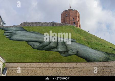 Vilnius, Lituanie. 13 septembre 2024. Le tableau géant de Land art intitulé 'Beyond Walls' de l'artiste franco-suisse Saype (Guillaume Legros) est vu sur la pente de la colline de Gediminas à Vilnius. La murale représentant deux mains serrées symbolise la coopération culturelle entre la Lituanie et la France et proclame l'idée d'unité humaine. Les peintures utilisées par l’artiste sont respectueuses de l’environnement et sont composées de pigments biodégradables à base de charbon de bois, de craie, d’eau. (Photo de Yauhen Yerchak/SOPA images/SIPA USA) crédit : SIPA USA/Alamy Live News Banque D'Images