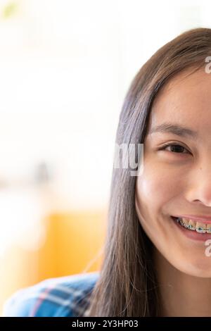 À la maison, portrait en gros plan d'une jeune femme asiatique souriante avec des accolades à la lumière naturelle, espace de copie Banque D'Images