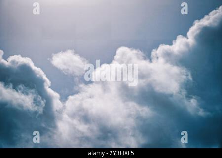 Découvrez la tranquillité capturée dans cette image de stock, où de doux cumulus flottent gracieusement dans un ciel bleu clair. La lumière du soleil filtre à travers Banque D'Images