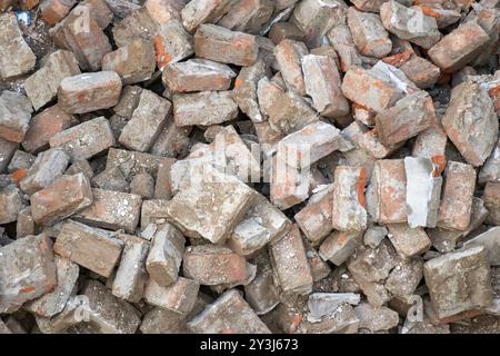 Pile de briques d'argile solides, utilisées dans les projets de construction, de réparation et de construction. Les briques rouges de la rénovation urbaine fournissent un arrière-plan, mettant en évidence le c Banque D'Images