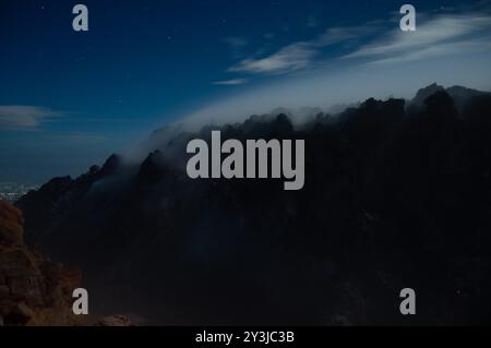 Vue nocturne de fumée sulfureuse du volcan Merapi sortant des rochers en silhouette noire Banque D'Images