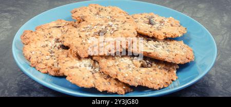 Biscuits à l'avoine faits maison frais avec du miel et différentes graines saines sur plaque bleue. Délicieux dessert croquant Banque D'Images