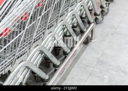 Vue rapprochée de chariots empilés dans un magasin de détail, présentant leurs cadres métalliques et leurs roues sur un sol carrelé. Banque D'Images