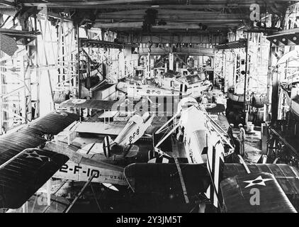 Vue du hangar du premier porte-avions USS Langley (CV-1) de la Marine des États-Unis dans les années 1920 Le plus grand avion au premier plan est un bombardier-torpilleur Douglas DT, avec ses ailes enlevées. D'autres avions sont des Vought VE-7 du Fighter Squadron 2 (VF-2), y compris les Bunos A5936 (marqué '2-F-9') et A5938 (marqué '2-F-8'). Les bateaux du navire sont arrimés le long des côtés du hangar. Photo de l'US Navy. Banque D'Images