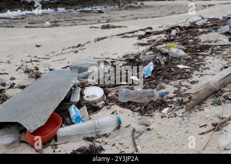 Une plage polluée sur Ko Samui, en Thaïlande, jonchée de bouteilles en plastique, de contenants alimentaires et de divers types de débris. Cette image met en évidence l'environnement Banque D'Images