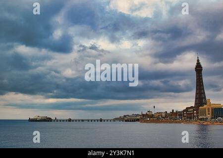 Une vue panoramique de Blackpool, avec l'emblématique Blackpool Tower et la jetée dans un ciel nuageux spectaculaire. La mer calme reflète l'atmosp couvert Banque D'Images