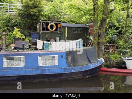 Un vieux bateau bleu et étroit amarré à côté de hangars en bois avec lavage sur la ligne sur le canal rochdale près du pont hebden Banque D'Images