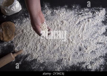 Portrait d'une femme. La diffusion de la farine blanche sur une table de cuisine noir Banque D'Images