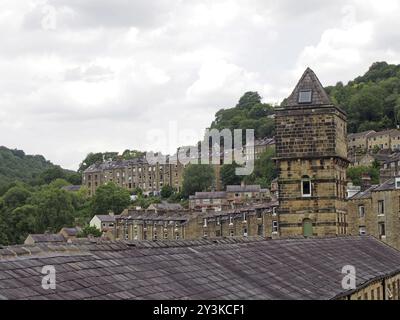 Une vue sur les rues escarpées à flanc de colline dans hebden pont entre les arbres d'été avec la tour du bâtiment historique du moulin à noix à l'avant Banque D'Images