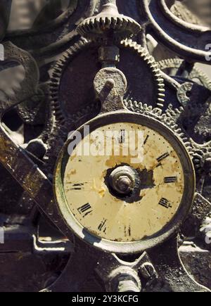 Ancienne horloge en fer rouillé avec visage altéré et mécanisme complexe exposé avec des rouages et des engrenages Banque D'Images