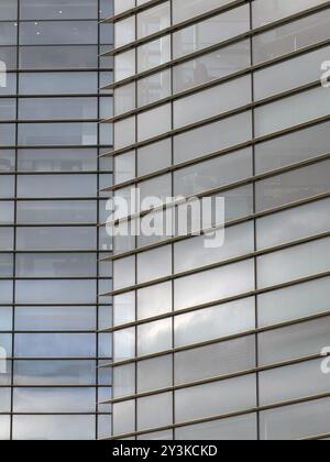 Architecture de bureau moderne plein cadre abstrait avec des formes géométriques de grands bâtiments reflétant le ciel nuageux bleu dans de grandes fenêtres en verre Banque D'Images