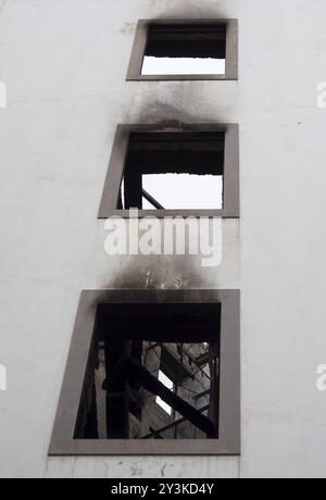 Une rangée de fenêtres dans un grand bâtiment industriel abandonné incendié avec des poutres carbonisées et un intérieur en ruine Banque D'Images