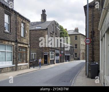 Mytholmroyd, West yorkshire, Royaume-uni, 13 juillet 2019 : une femme marchant devant des magasins et des maisons sur une nouvelle route dans le mytholmroyd West Yorkshire Banque D'Images