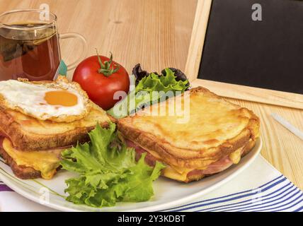 Snack avec sandwichs au jambon et au fromage, tasse de thé, de tomate et de salade fraîche. À côté de la plaque avec l'alimentation est un tableau noir et craie pour écrire messa Banque D'Images