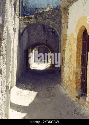 Une ruelle entre les bâtiments anciens de la ville de rhodes avec des arches basses et des portes Banque D'Images