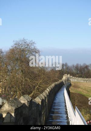 Une vue le long de la passerelle piétonne sur les remparts de la ville médiévale historique à york entouré d'arbres et de bâtiments de la ville Banque D'Images