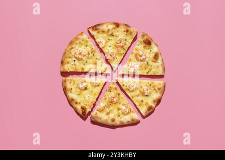 Pizza aux crevettes maison dans une lumière lumineuse minimaliste sur une table rose. Vue de dessus avec une pizza tranchée isolée sur un fond coloré vibrant Banque D'Images