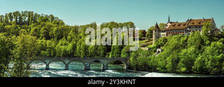 Panorama sur une journée ensoleillée avec le château de Laufen, entourée de forêt, avec un pont de pierre sur le Rhin, dans la ville Laufen-Uhwiesen, Suisse Banque D'Images