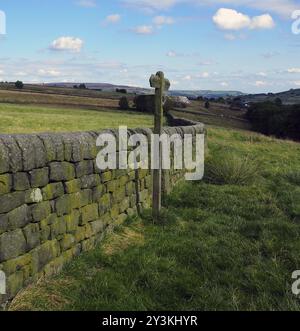 Campagne ouverte avec panneau de direction à côté d'un mur de pierre sèche avec des champs verts et Mooland au loin dans le yorkshire angleterre Banque D'Images