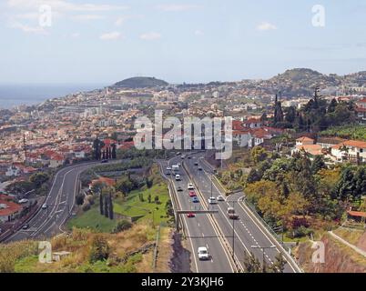 Une vue aérienne du paysage urbain de funchal montrant le trafic sur l'autoroute principale VR1 qui mène à la ville avec la côte visible au loin Banque D'Images