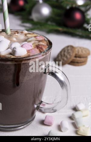 Boisson sucrée traditionnelle de Noël avec une tasse de chocolat chaud avec guimauves mini sur le dessus. Les cookies et les guimauves à la table Banque D'Images