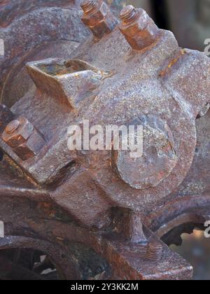 Gros plan d'un axe de boulons et d'une roue sur de vieilles machines industrielles abandonnées rouillées Banque D'Images