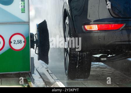 Black car est lavé par une machine automatique de lavage de voiture sur une journée d'hiver brillante Banque D'Images