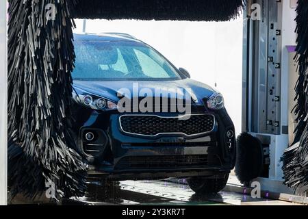 La voiture noire moderne se nettoie dans un lave-auto automatique Banque D'Images