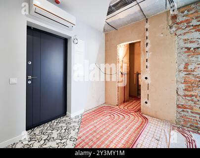 Comparaison de vieil appartement avec tuyaux de chauffage au sol et nouvel appartement rénové avec un design intérieur moderne. Salle de bain, couloir avec plancher chauffant avant et après rénovation. Banque D'Images