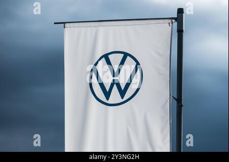 Eine Flagge mit dem logo des Automobilherstellers Volkswagen weht im Abendlicht vor dunklem Himmel im Wind. Rottweil Baden-Württemberg Deutschland *** Un drapeau avec le logo du constructeur automobile Volkswagen vole dans le vent dans la lumière du soir contre un ciel sombre Rottweil Baden Württemberg Allemagne Banque D'Images