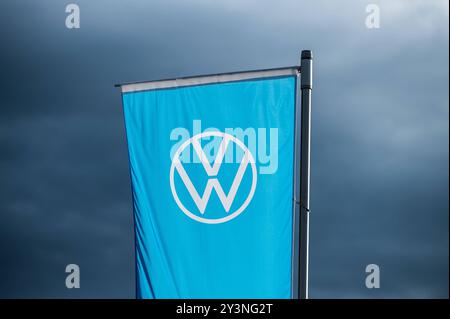 Eine Flagge mit dem logo des Automobilherstellers Volkswagen weht im Abendlicht vor dunklem Himmel im Wind. Rottweil Baden-Württemberg Deutschland *** Un drapeau avec le logo du constructeur automobile Volkswagen vole dans le vent dans la lumière du soir contre un ciel sombre Rottweil Baden Württemberg Allemagne Banque D'Images