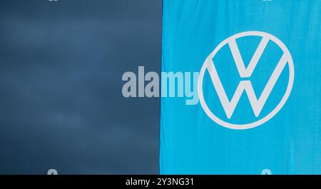 Eine Flagge mit dem logo des Automobilherstellers Volkswagen weht im Abendlicht vor dunklem Himmel im Wind. Rottweil Baden-Württemberg Deutschland *** Un drapeau avec le logo du constructeur automobile Volkswagen vole dans le vent dans la lumière du soir contre un ciel sombre Rottweil Baden Württemberg Allemagne Banque D'Images