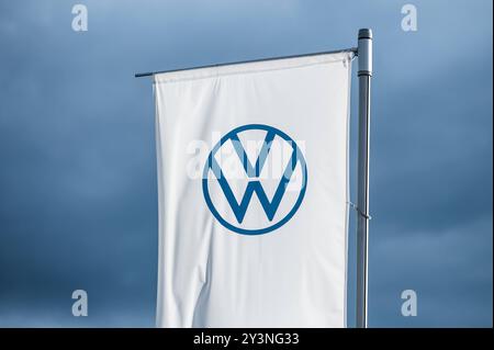 Eine Flagge mit dem logo des Automobilherstellers Volkswagen weht im Abendlicht vor dunklem Himmel im Wind. Rottweil Baden-Württemberg Deutschland *** Un drapeau avec le logo du constructeur automobile Volkswagen vole dans le vent dans la lumière du soir contre un ciel sombre Rottweil Baden Württemberg Allemagne Banque D'Images