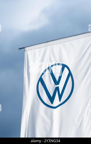 Eine Flagge mit dem logo des Automobilherstellers Volkswagen weht im Abendlicht vor dunklem Himmel im Wind. Rottweil Baden-Württemberg Deutschland *** Un drapeau avec le logo du constructeur automobile Volkswagen vole dans le vent dans la lumière du soir contre un ciel sombre Rottweil Baden Württemberg Allemagne Banque D'Images