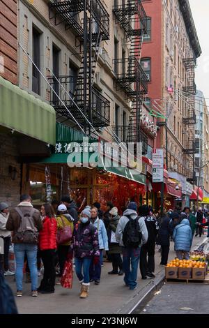 New York, États-Unis -14 septembre 2024 : rue animée avec des gens marchant parmi les magasins avec des panneaux chinois et des évasions de feu typiques de New York. Banque D'Images
