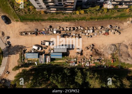 Vue aérienne d'un chantier de construction présentant divers matériaux et équipements de construction. Le site comprend des piles de briques, des blocs de béton. Sur Banque D'Images
